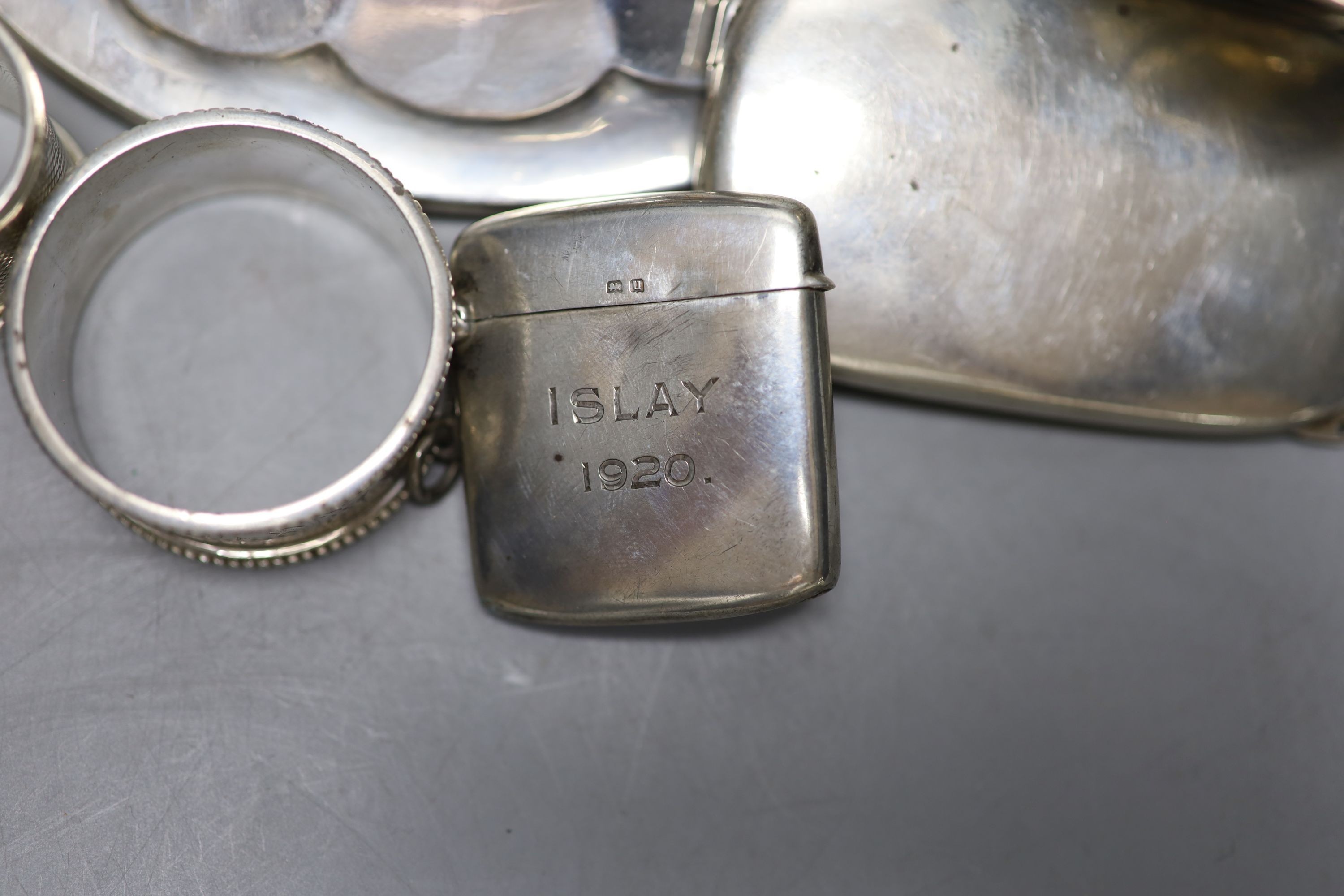 A Scottish silver mounted oval inkwell, 13.2cm, a small silver bowl, silver vesta case, silver cigarette case, two silver napkin rings and two other items.